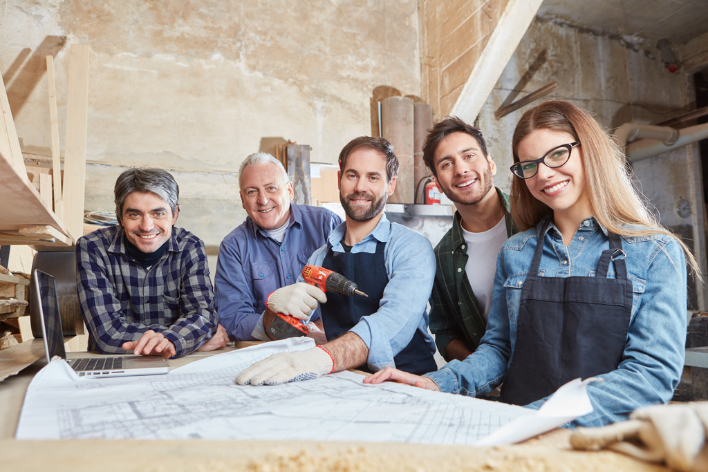 Ein Handwerkerteam posiert an einem Tisch mit Blaupause